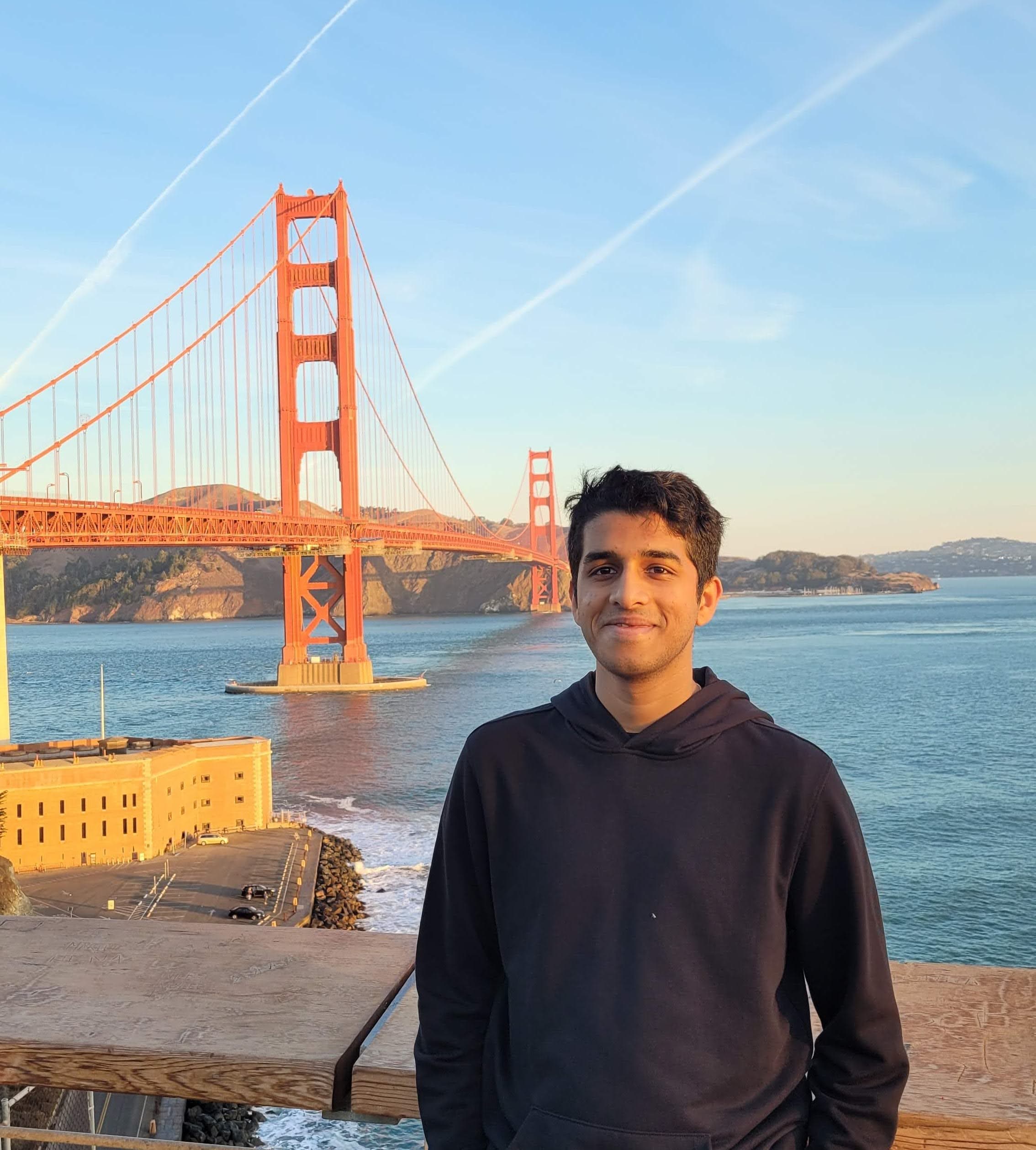 Aniruddhan standing in front of the Golden Gate Bridge in San Francisco at golden hour